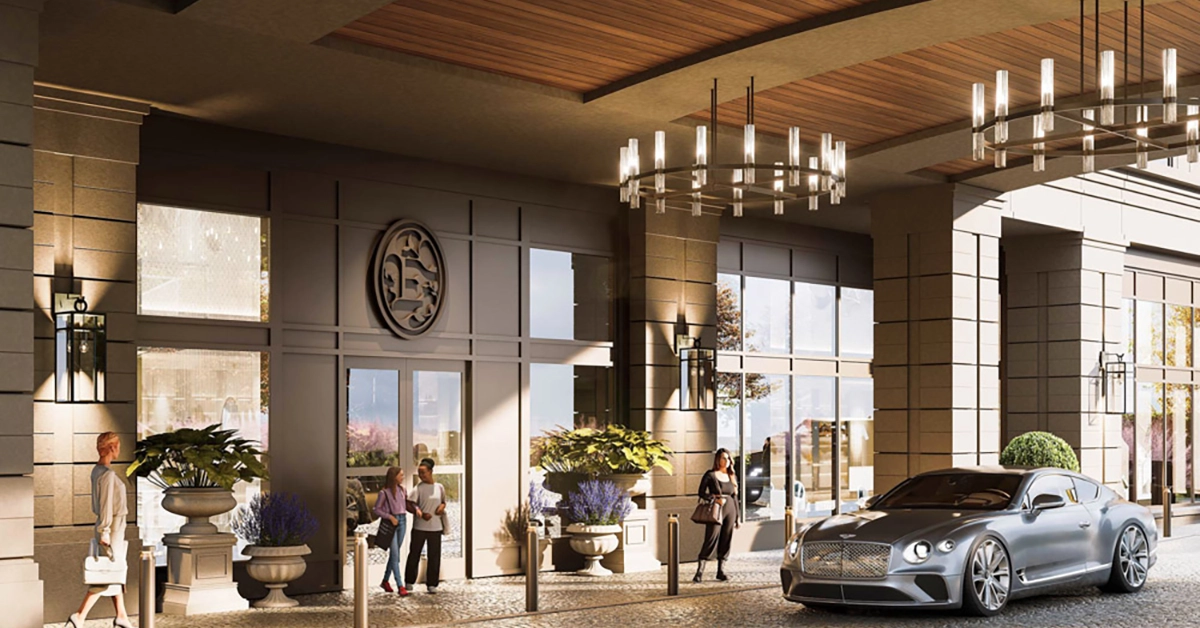 Front arrival plaza of Elyse Buckhead luxury residential building with landscaping, covered entry, and a parked silver