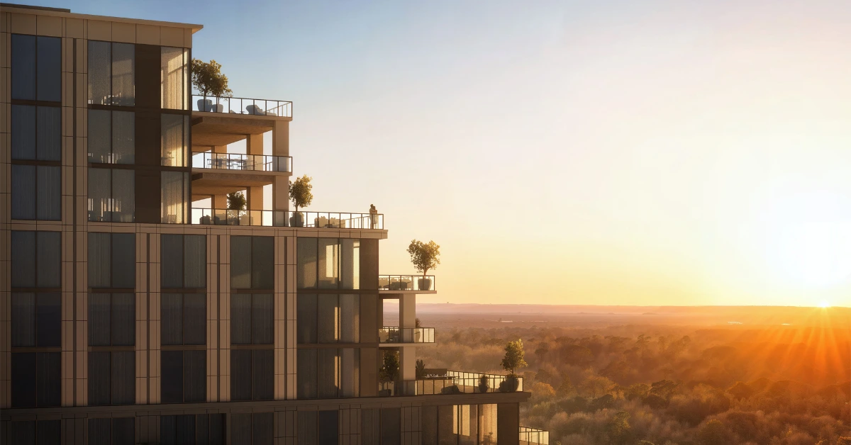 Modern condo tower with glass balconies and terraces overlooking trees at sunrise.