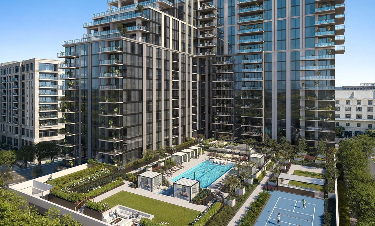 Aerial view of residential towers with a pool deck, lawns, cabanas, and pickleball courts.