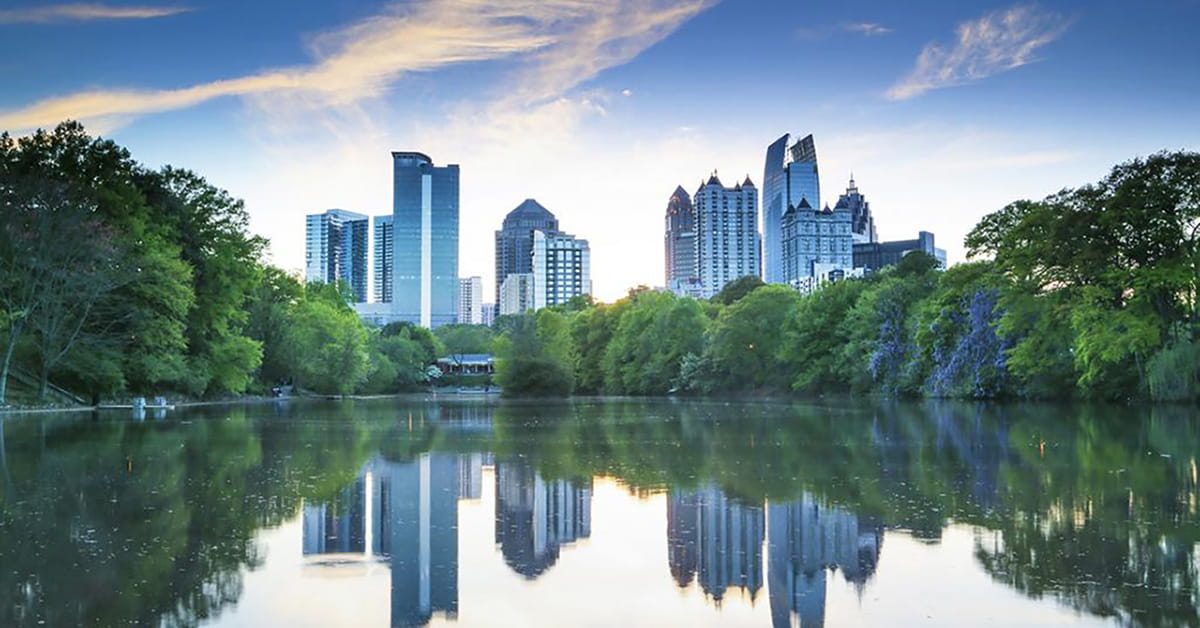 Atlanta skyline reflected in calm lake with trees and sunset sky